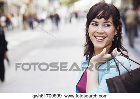 Stock Photo - Close-up of a mid adult woman holding a shopping bag . Fotosearch