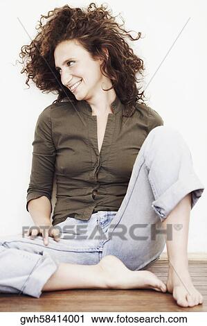 Stock Image - Close-up of a mid adult woman sitting on the floor and looking sideways. Fotosearch