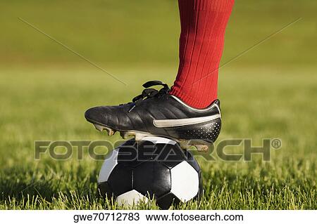 Stock Image - Close-up of a person's foot resting on a soccer ball. Fotosearch
