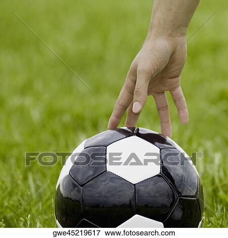Stock Photo - Close-up of a person's hand touching a soccer ball. Fotosearch
