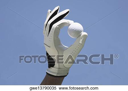 Stock Photography - Close-up of a person's hand wearing a glove and holding a golf ball. Fotosearch