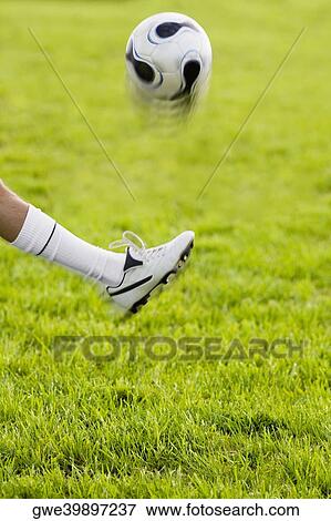 Stock Photo - Close-up of a person's leg kicking a soccer ball. Fotosearch