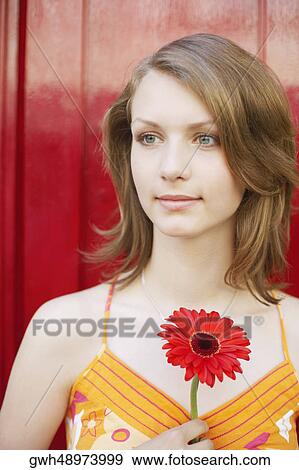 Close-up of a teenage girl holding a flower View Large Photo Image Stock Photo - Close-up of a teenage girl holding a flower. Fotosearch