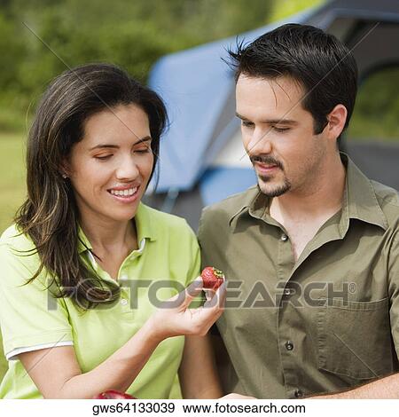 Close-up of a young couple looking at a strawberry View Large Photo Image Stock Photo - Close-up of a young couple looking at a strawberry. Fotosearch