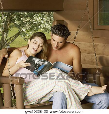 Close-up of a young couple reading a magazine View Large Photo Image Stock Image - Close-up of a young couple reading a magazine. Fotosearch
