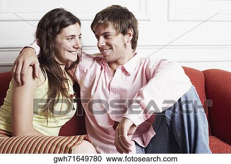 Close-up of a young couple sitting on a couch and looking at each other View Large Photo Image Stock Image - Close-up of a young couple sitting on a couch and looking at each other. Fotosearch