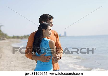 Stock Photography - Close-up of a young couple standing on the beach. Fotosearch