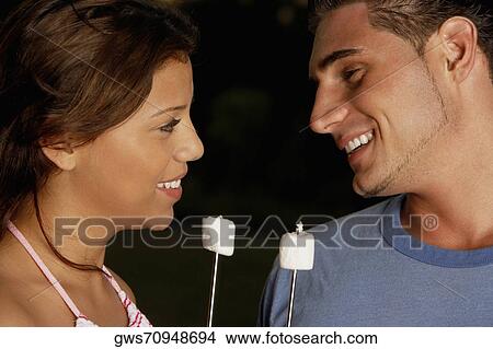 Picture - Close-up of a young man and a teenage girl holding marshmallows. Fotosearch