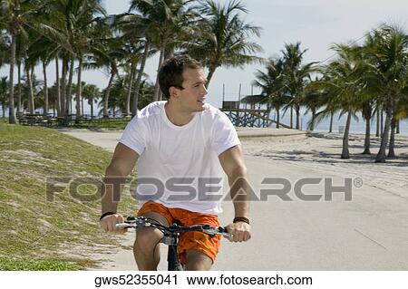 Stock Image - Close-up of a young man cycling on the road. Fotosearch