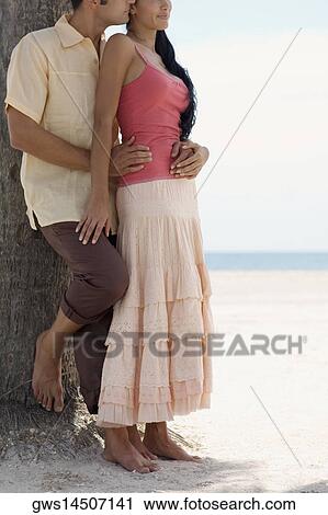 Stock Image - Close-up of a young man embracing a young woman on the beach. Fotosearch