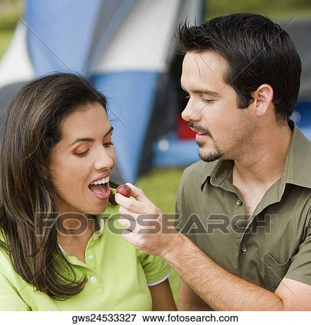Stock Photo - Close-up of a young man feeding a young woman a cherry. Fotosearch