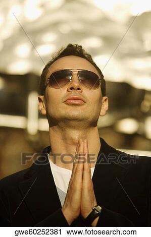 Stock Image - Close-up of a young man in a prayer position. Fotosearch