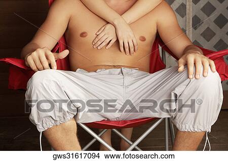 Close-up of a young man sitting in an armchair with a young woman embracing him from behind View Large Photo Image Picture - Close-up of a young man sitting in an armchair with a young woman embracing him from behind. Fotosearch