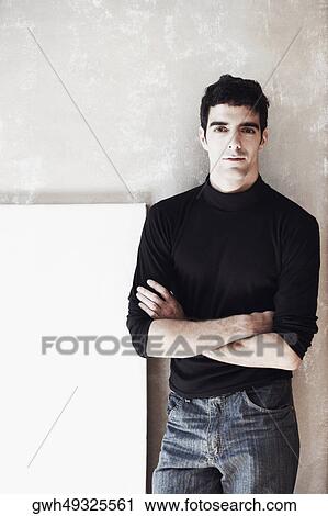 Stock Image - Close-up of a young man standing with his arms crossed. Fotosearch