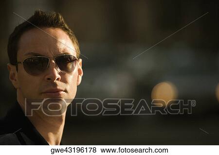 Close-up of a young man wearing sunglasses View Large Photo Image Stock Photo - Close-up of a young man wearing sunglasses. Fotosearch