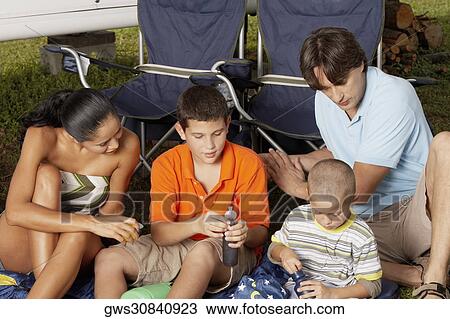 Close-up of a young woman and a mid adult man sitting with their two children View Large Photo Image Stock Image - Close-up of a young woman and a mid adult man sitting with their two children. Fotosearch