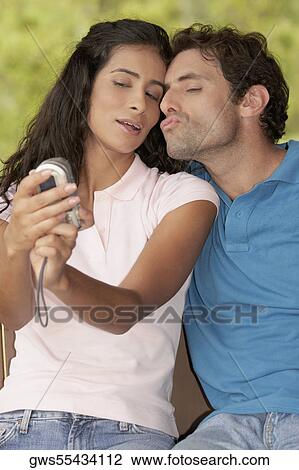 Stock Image - Close-up of a young woman and a mid adult man photographing themselves. Fotosearch