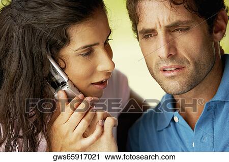 Close-up of a young woman and a mid adult man using a mobile phone View Large Photo Image Stock Image - Close-up of a young woman and a mid adult man using a mobile phone. Fotosearch