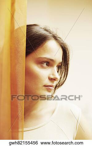 Close-up of a young woman behind a curtain View Large Photo Image Stock Photograph - Close-up of a young woman behind a curtain. Fotosearch