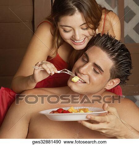 Close-up of a young woman feeding fruit salad to a young man View Large Photo Image Stock Image - Close-up of a young woman feeding fruit salad to a young man. Fotosearch