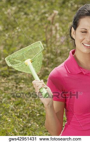 Stock Image - Close-up of a young woman holding a butterfly net. Fotosearch