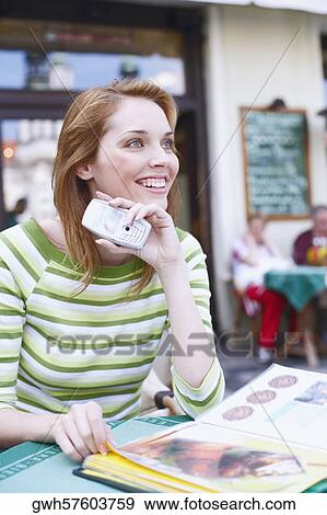 Stock Photo - Close-up of a young woman holding a mobile phone in a restaurant . Fotosearch