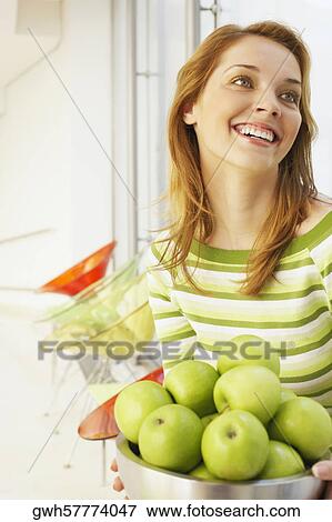 Close-up of a young woman holding a bowl of green apples View Large Photo Image Stock Photo - Close-up of a young woman holding a bowl of green apples. Fotosearch