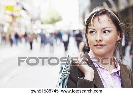 Close-up of a young woman holding a shopping bag View Large Photo Image Stock Photography - Close-up of a young woman holding a shopping bag . Fotosearch