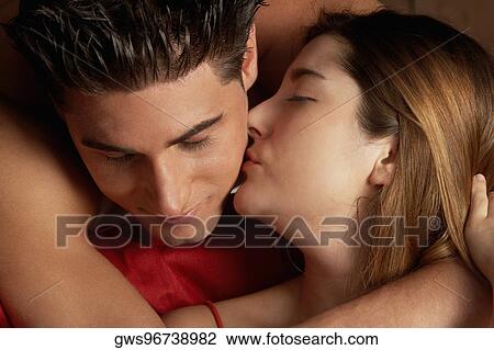 Stock Image - Close-up of a young woman kissing a young man on his cheek. Fotosearch
