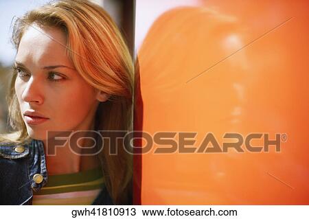 Close-up of a young woman leaning against a wall View Large Photo Image Stock Image - Close-up of a young woman leaning against a wall . Fotosearch