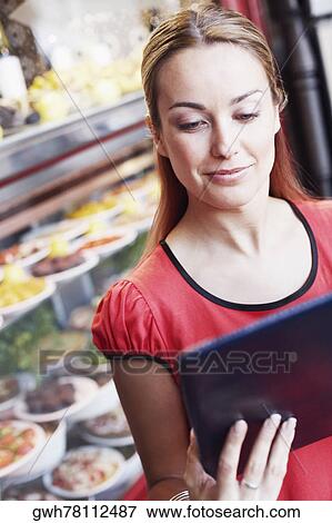 Close-up of a young woman reading a menu in a restaurant View Large Photo Image Stock Photo - Close-up of a young woman reading a menu in a restaurant . Fotosearch