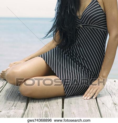Stock Photograph - Close-up of a young woman sitting on a pier. Fotosearch