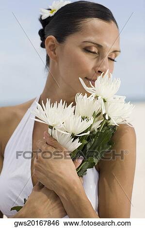 Close-up of a young woman smelling a flower View Large Photo Image Stock Photograph - Close-up of a young woman smelling a flower. Fotosearch