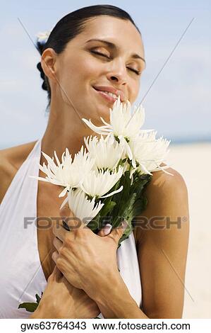 Stock Image - Close-up of a young woman smelling flowers. Fotosearch