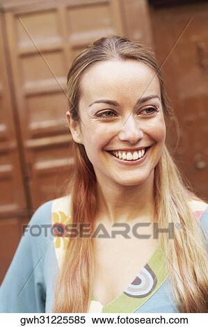 Close-up of a young woman smiling and looking away View Large Photo Image Stock Photography - Close-up of a young woman smiling and looking away. Fotosearch