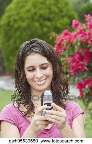 Close-up of a young woman using a mobile phone and smiling View Large Photo Image Stock Image - Close-up of a young woman using a mobile phone and smiling. Fotosearch