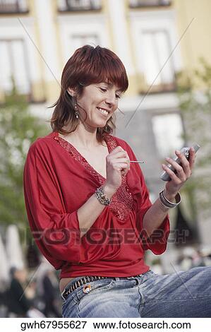 Stock Photo - Close-up of a young woman using a personal data assistant . Fotosearch