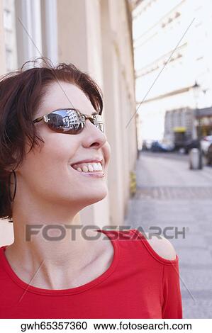 Stock Image - Close-up of a young woman wearing sunglasses and smiling . Fotosearch