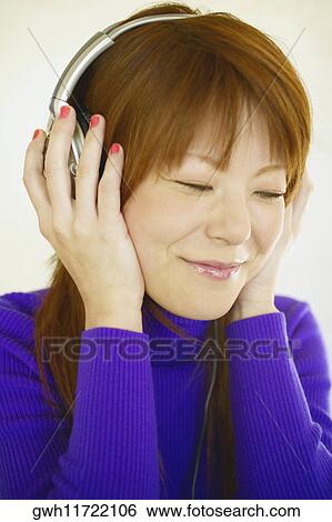 Stock Photograph - Close-up of a young woman wearing headphones. Fotosearch