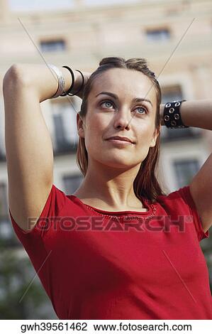 Close-up of a young woman with her hands behind head View Large Photo Image Stock Image - Close-up of a young woman with her hands behind head . Fotosearch
