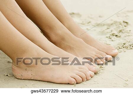 Stock Photo - Close-up of the feet of two people on sand. Fotosearch