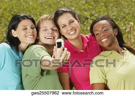 Stock Image - Close-up of three young women and a young man photographing themselves. Fotosearch