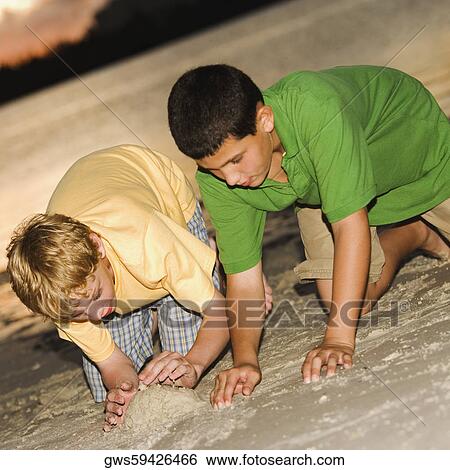 Stock Photograph - Close-up of two boys making a sand castle. Fotosearch
