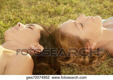 Close-up of two mid adult women lying on the grass with their eyes closed View Large Photo Image Stock Image - Close-up of two mid adult women lying on the grass with their eyes closed. Fotosearch