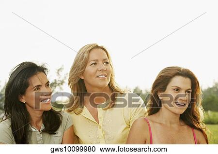 Stock Image - Close-up of two mid adult women with a mature woman looking away. Fotosearch