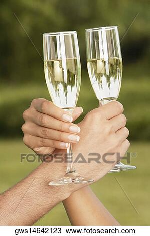 Stock Image - Close-up of two people's hands toasting with champagne flutes. Fotosearch