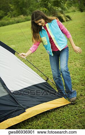 Stock Image - Girl adjusting a tent. Fotosearch