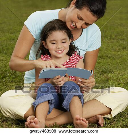Girl sitting on her mother's lap and reading a book View Large Photo Image Stock Photo - Girl sitting on her mother's lap and reading a book. Fotosearch
