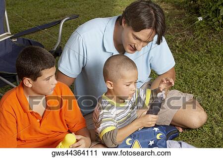 High angle view of a mid adult man and his two children sitting on the grass View Large Photo Image Stock Image - High angle view of a mid adult man and his two children sitting on the grass. Fotosearch