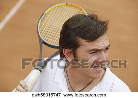 High angle view of a mid adult man holding a tennis racket on a tennis court View Large Photo Image Stock Photo - High angle view of a mid adult man holding a tennis racket on a tennis court. Fotosearch